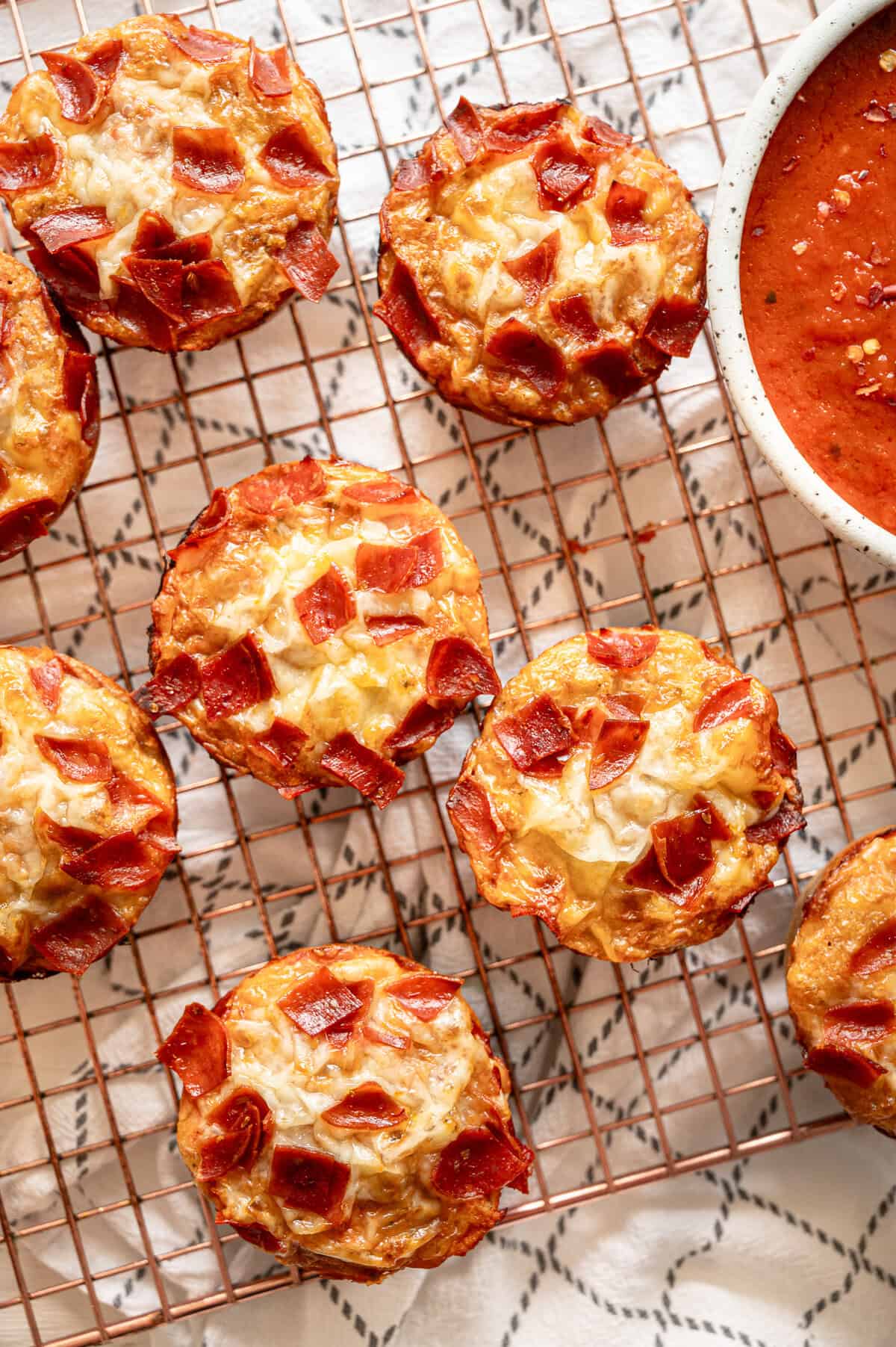 Pepperoni pizza muffins straight from the oven on a cooling rack.