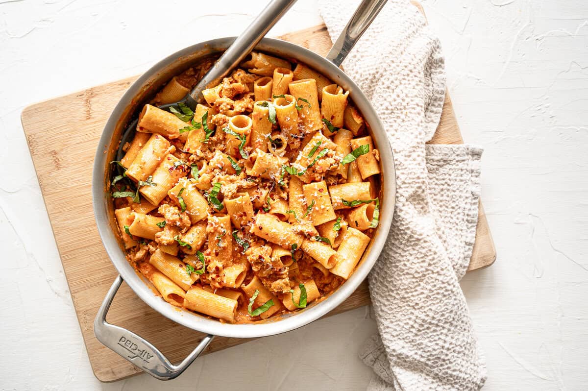 A pan of creamy tomato rigatoni with grated Parmesan cheese ready to serve.