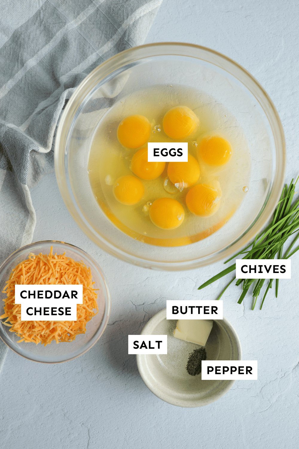 Ingredients for cheesy scrambled eggs measured out and labeled.