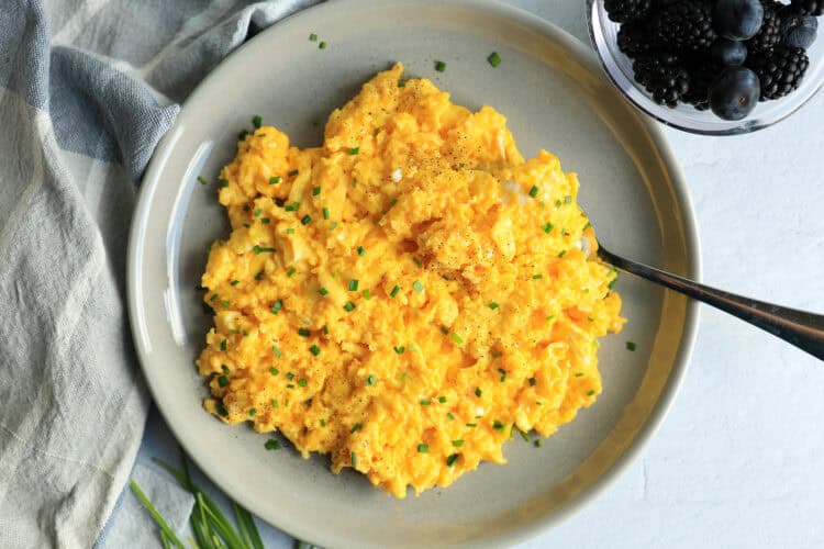 Scrambled eggs with cheddar cheese and chopped chives mixed in.