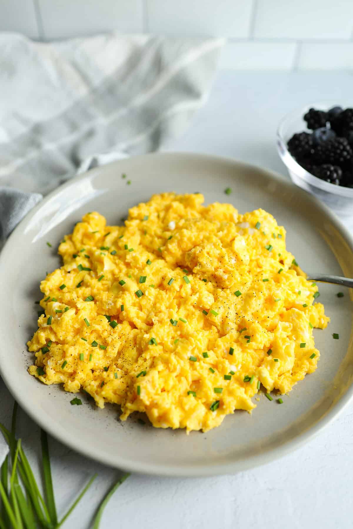 Scrambled eggs with cheese served with blackberries and blueberries.