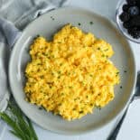 Cheesy scrambled eggs served with a bowl of fresh berries.