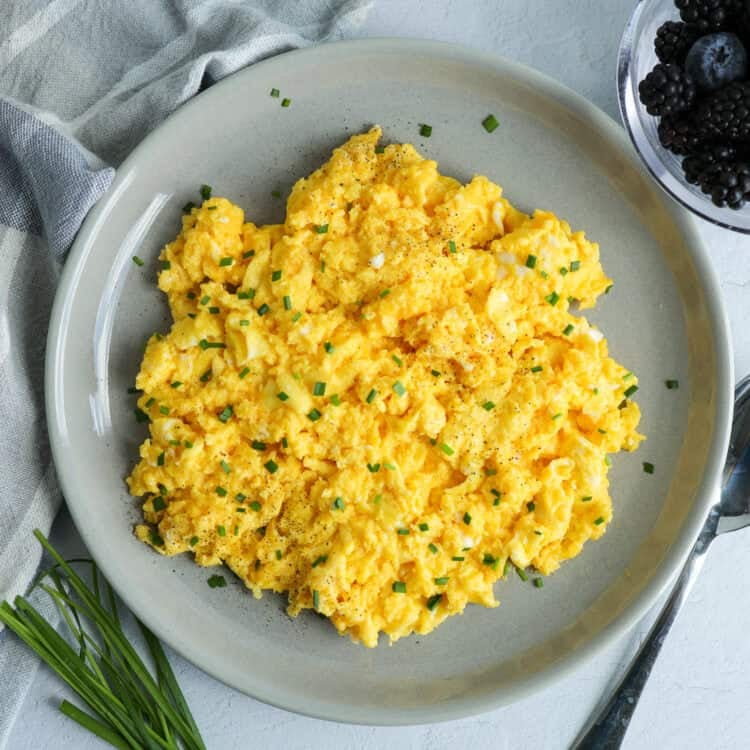 Cheesy scrambled eggs served with a bowl of fresh berries.