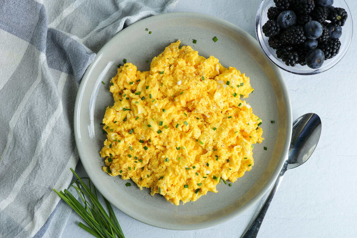 Cheesy scrambled eggs served with a bowl of fresh berries.