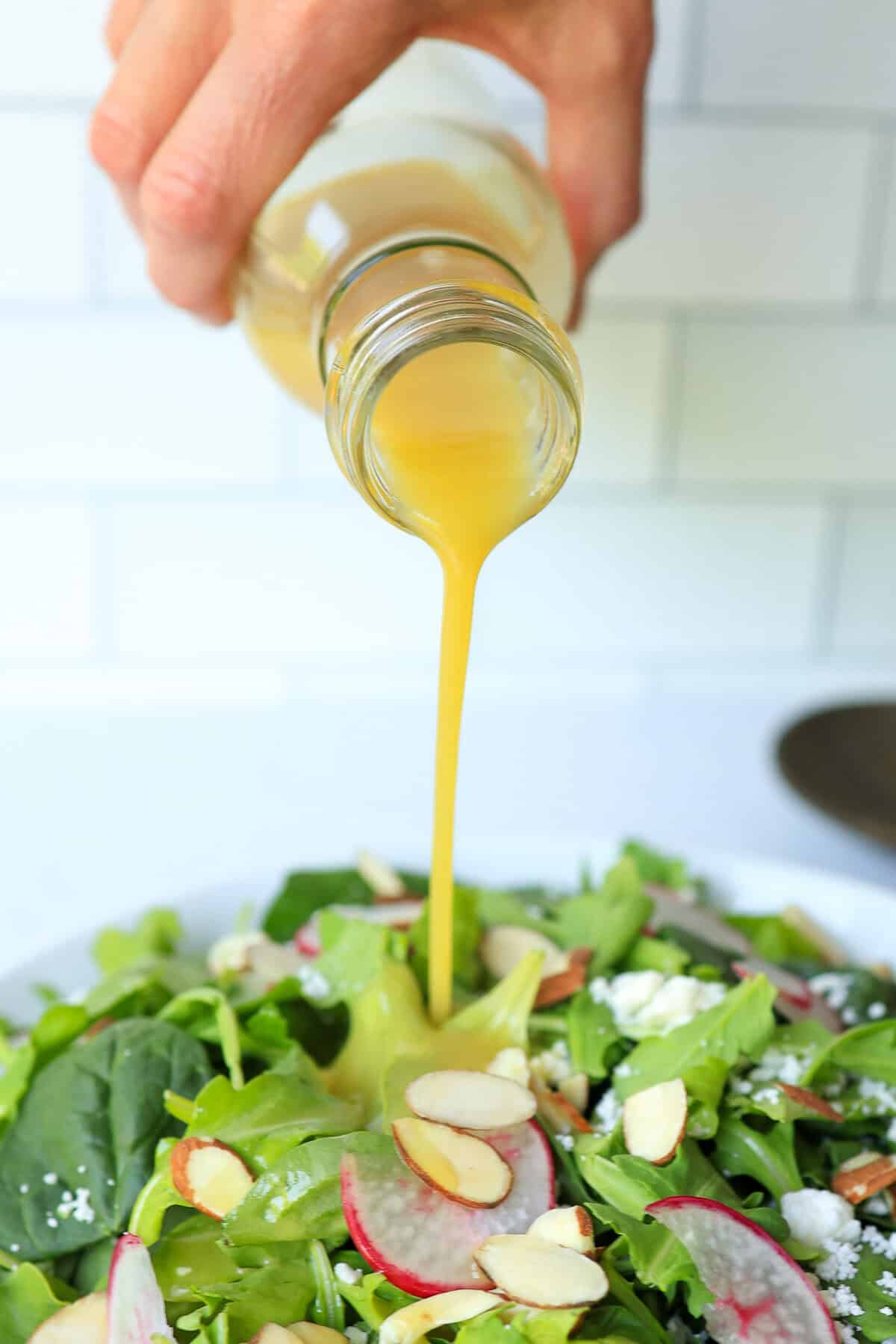 Honey dijon dressing poured on to a salad.