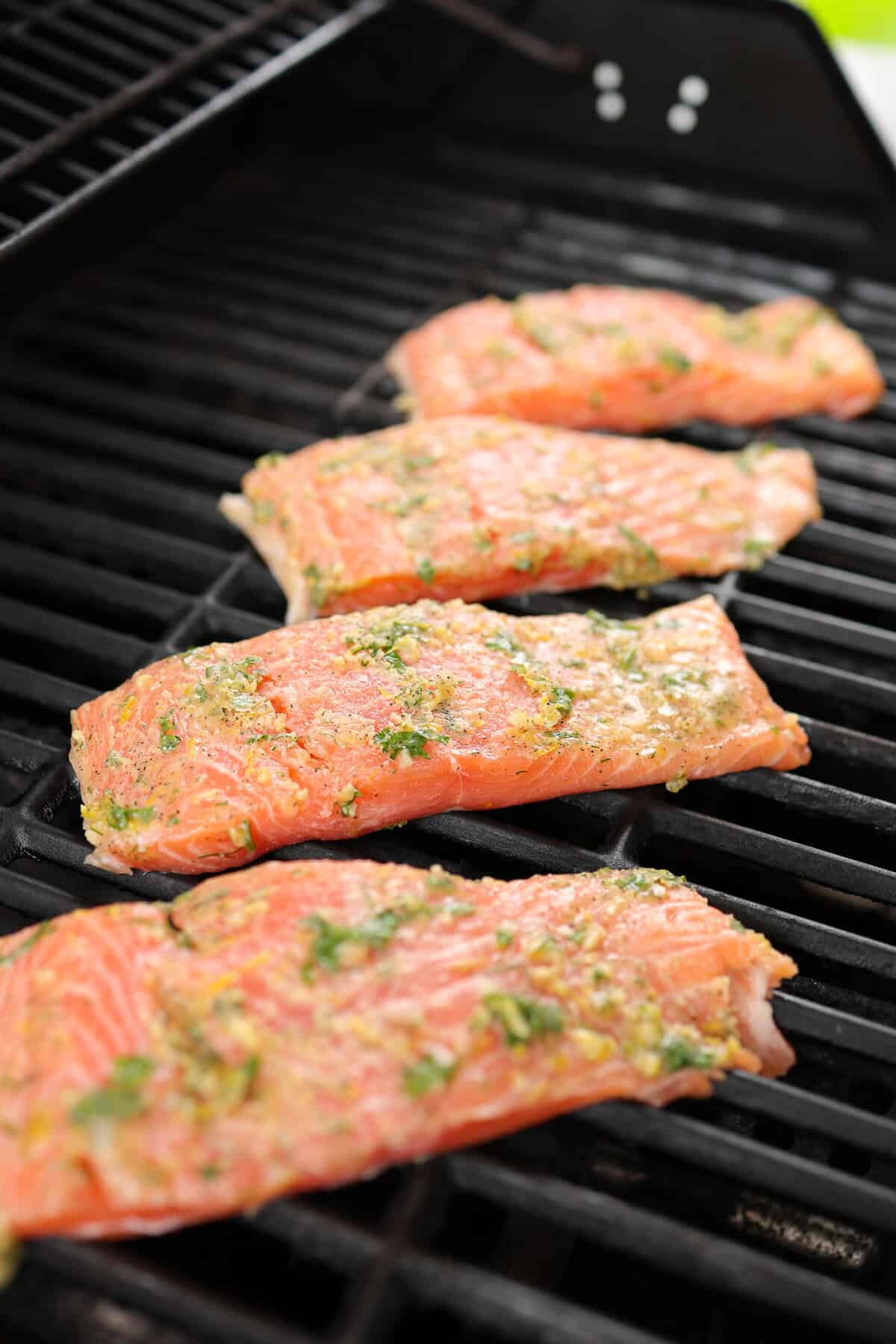 Salmon fillets on a grill with lemon garlic marinade on top.