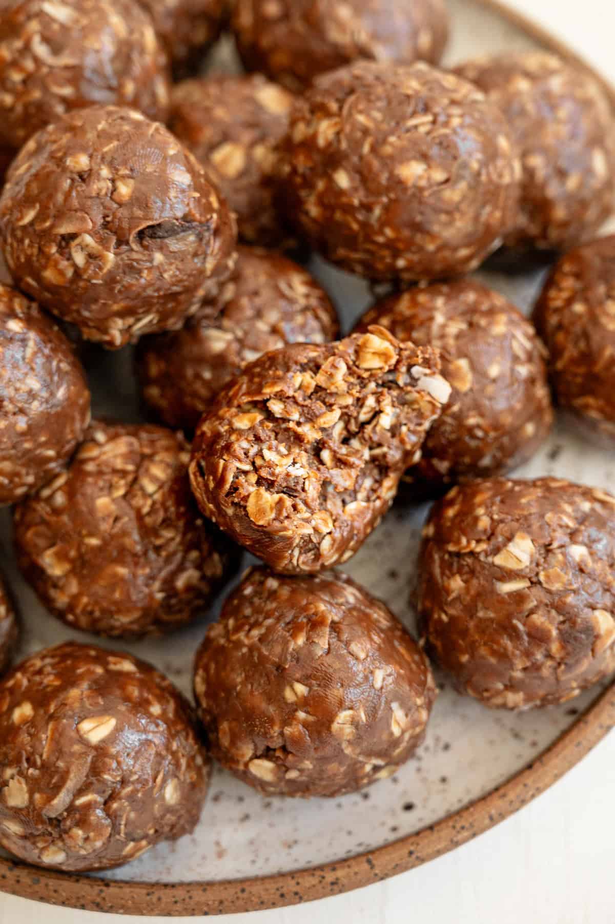 A plate of chocolate peanut butter oatmeal bites with one broken up to see the inside.