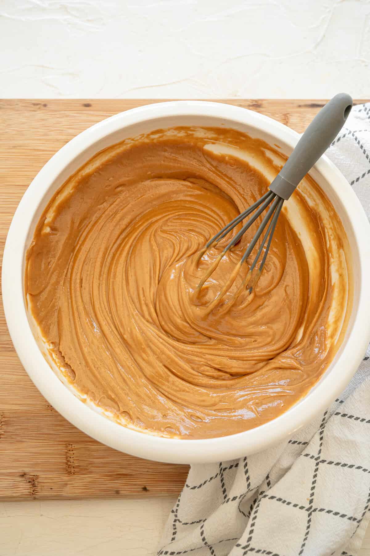 Creamy peanut butter and honey being whisked together in a bowl.