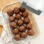 A glass container of chocolate peanut butter oatmeal bites in a single layer ready to be stored in the freezer.