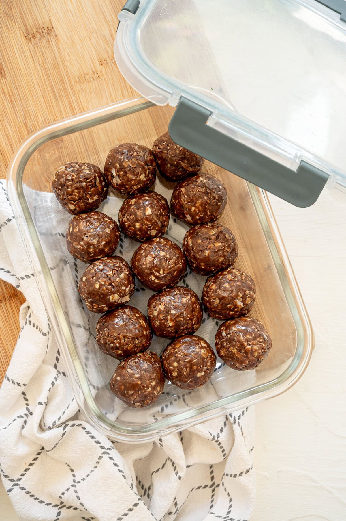 A glass container of chocolate peanut butter oatmeal bites in a single layer ready to be stored in the freezer.