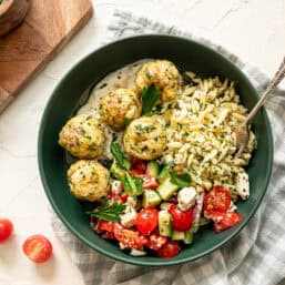 Greek feast with chicken meatballs, tzatziki sauce, cucumber and tomato salad, and lemon feta orzo pasta.