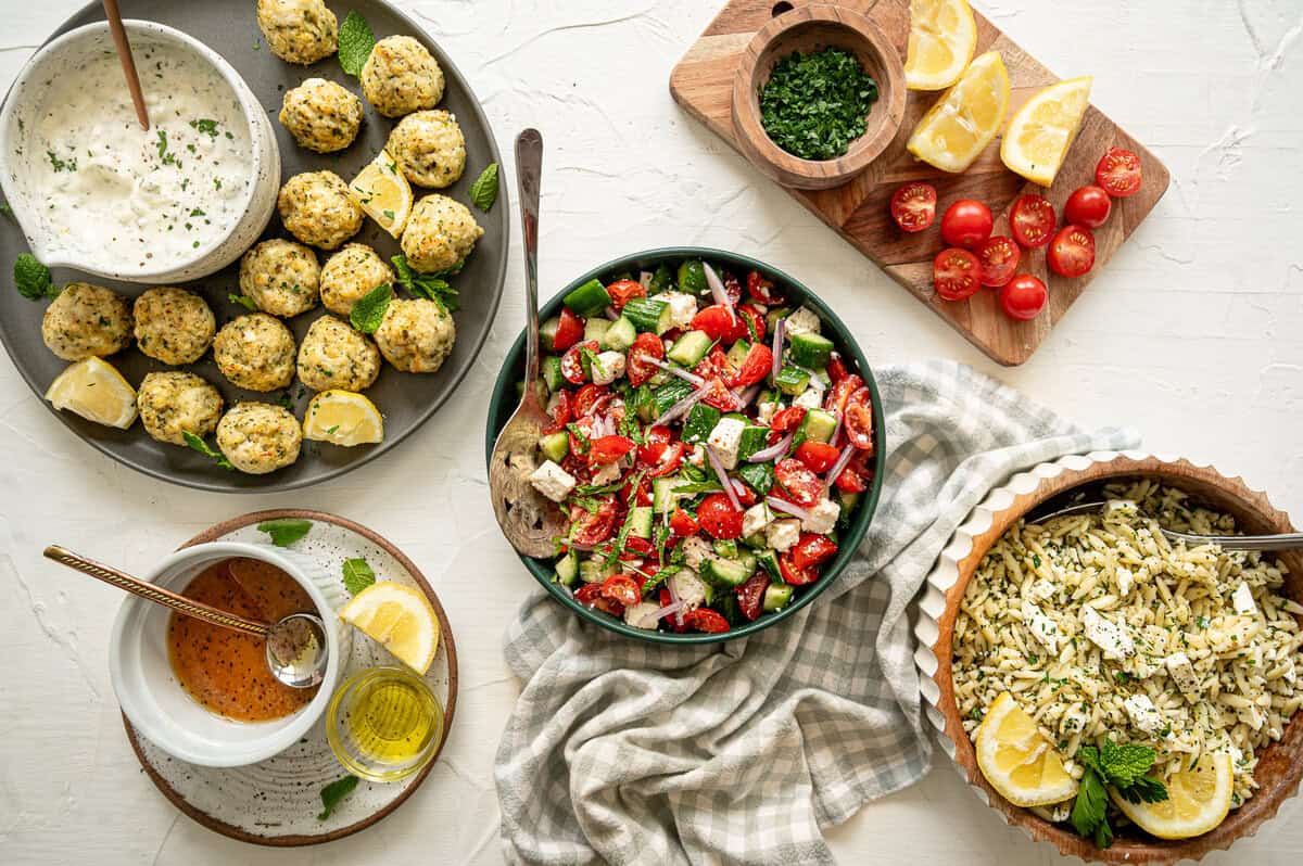 Greek feast with chicken meatballs, tzatziki sauce, cucumber and tomato salad, and lemon feta orzo pasta.