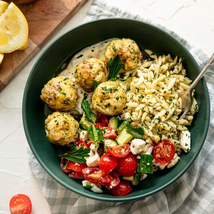 Greek feast with chicken meatballs, tzatziki sauce, cucumber and tomato salad, and lemon feta orzo pasta.