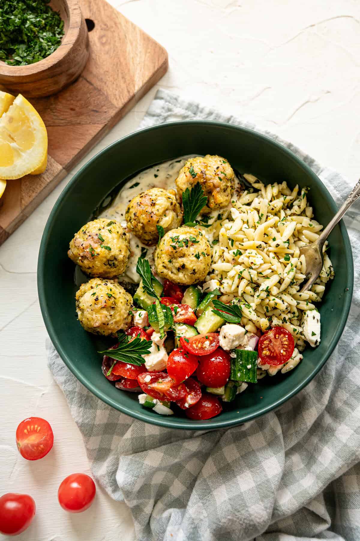 Greek feast with chicken meatballs, tzatziki sauce, cucumber and tomato salad, and lemon feta orzo pasta.