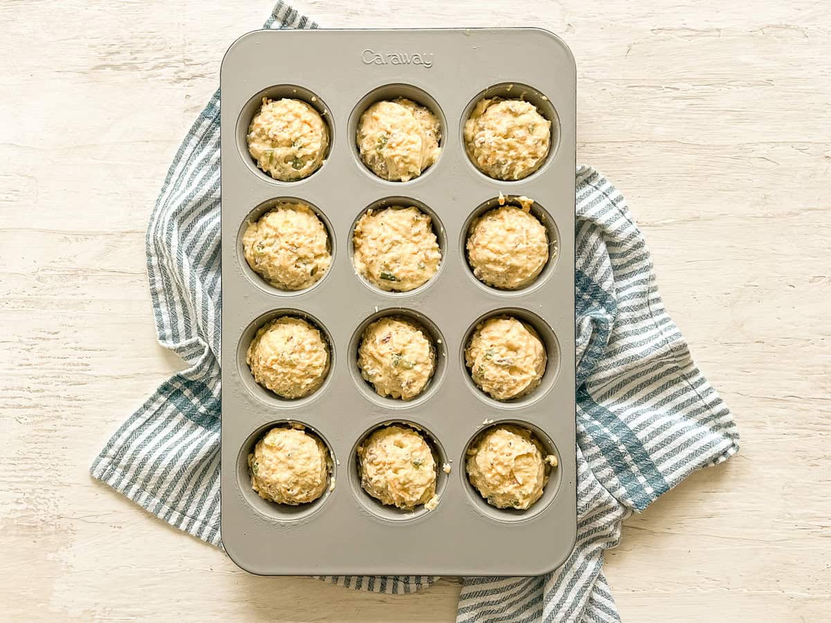 A muffin pan full with savory breakfast muffins batter ready to be baked.