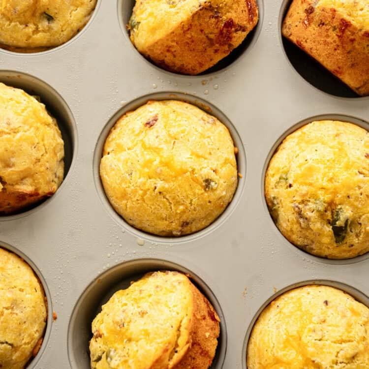 Savory breakfast muffins on their sides in a muffin pan cooling.