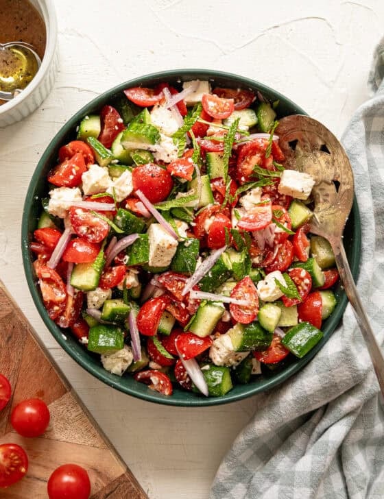 A bowl of salad with tomatoes, cucumbers and onions.