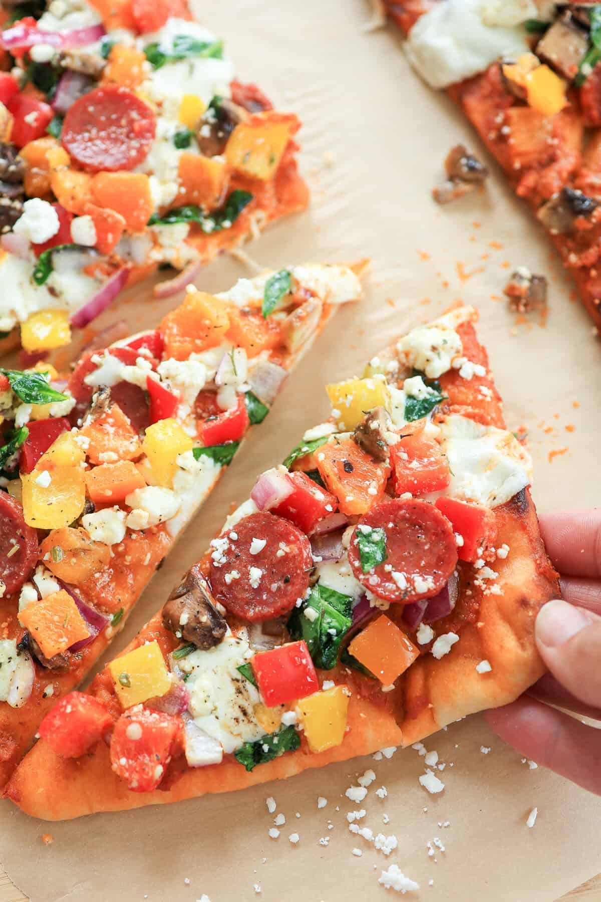 Flatbread pizza triangle with lots of veggies and Feta on it.