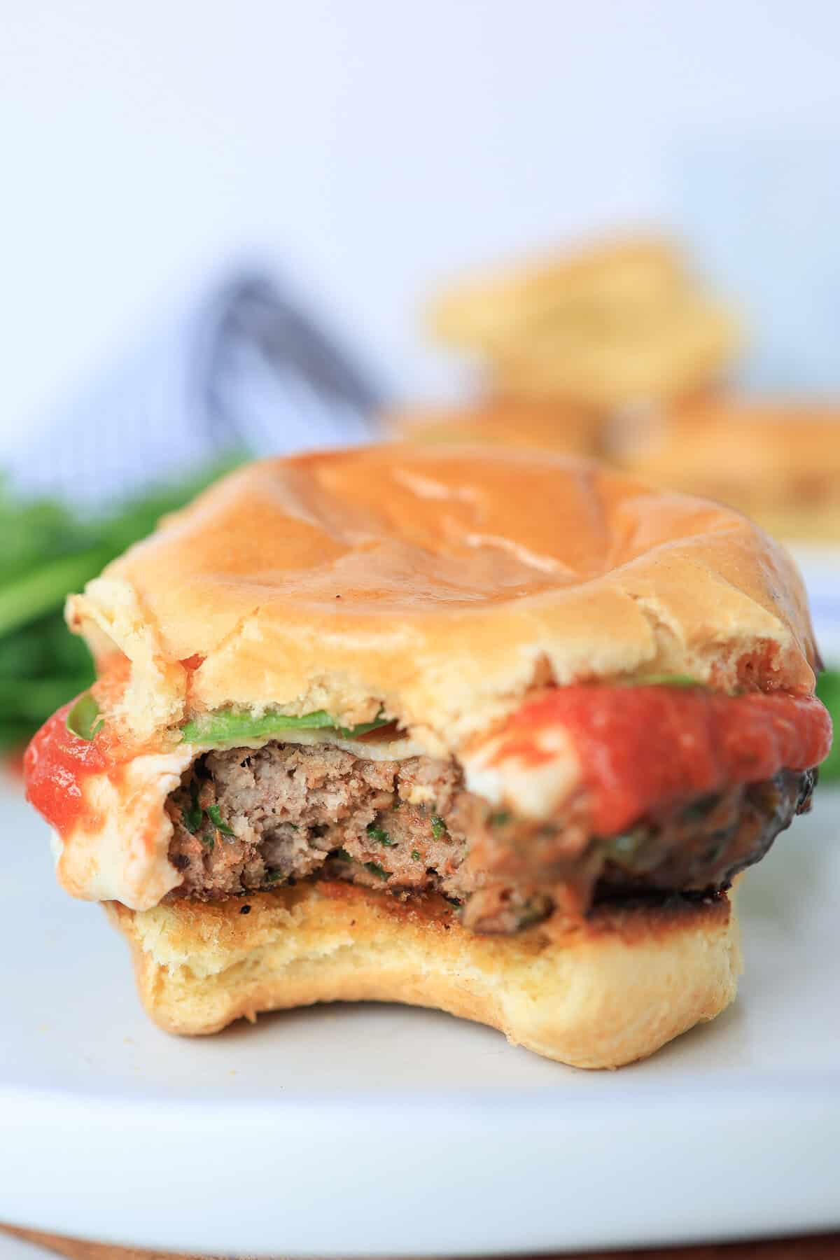 slider burgers on brioche bun with bite out of it.