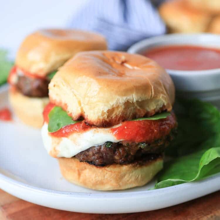 Mini Italian sliders on a plate with extra marinara.