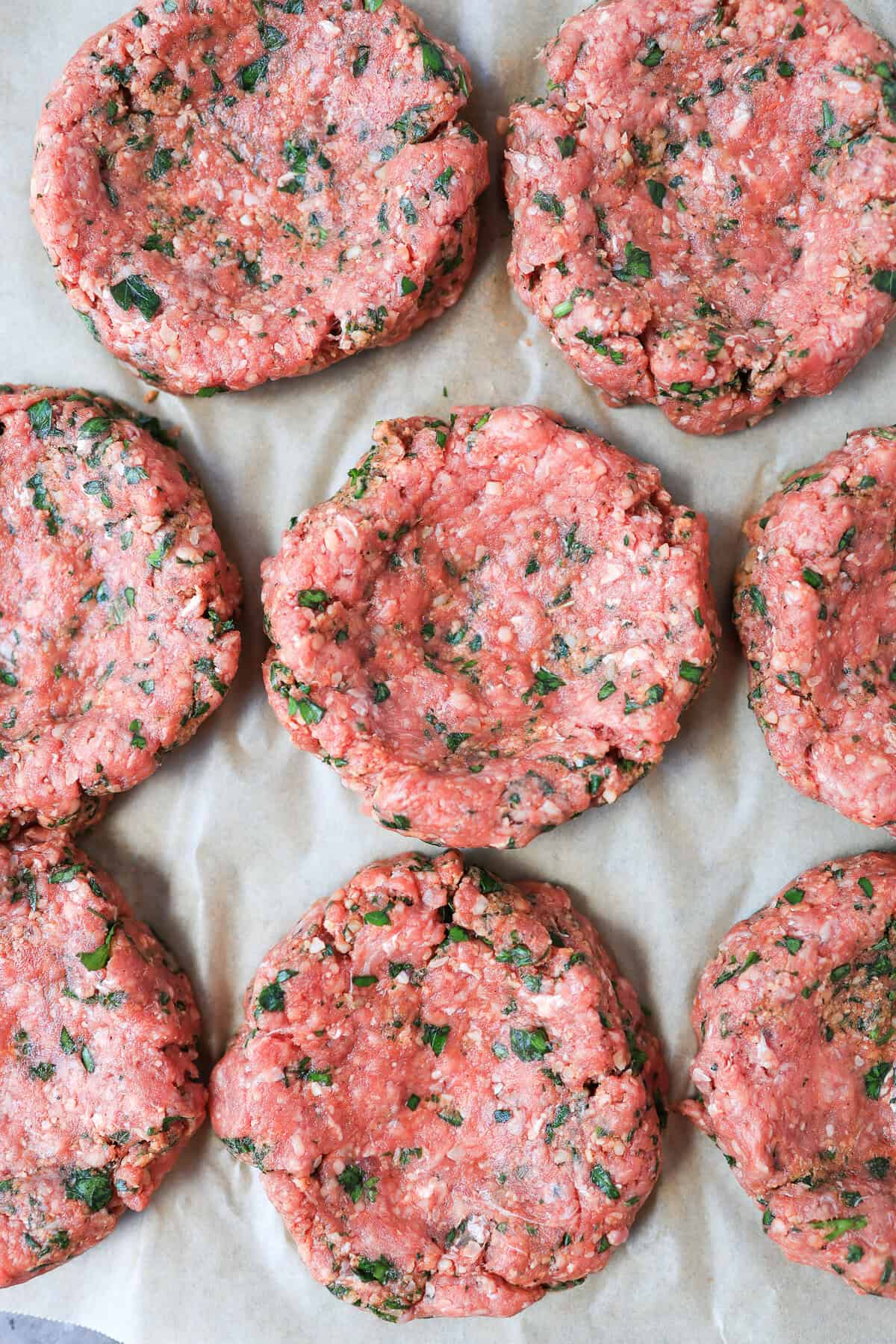 Small burger patties on parchment paper.