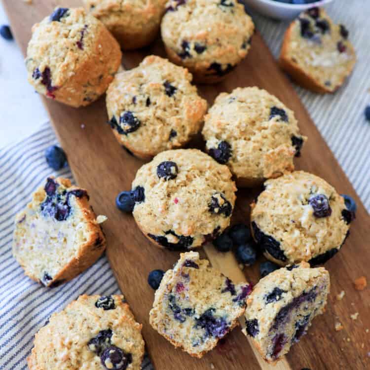 Blueberry oatmeal muffins on a cutting board with several cut in half and buttered.