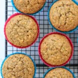 Zucchini carrot muffins in colorful silicone muffin liners on a cooling rack.