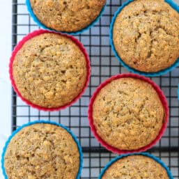 Zucchini carrot muffins in colorful silicone muffin liners on a cooling rack.