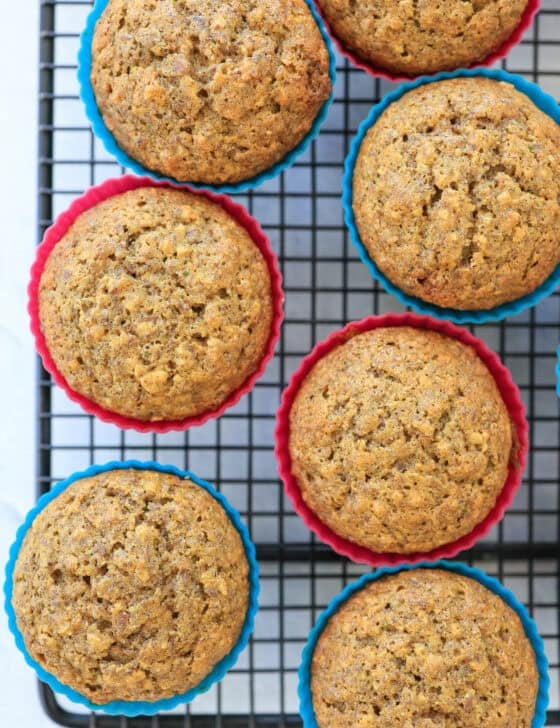 Zucchini carrot muffins in colorful silicone muffin liners on a cooling rack.