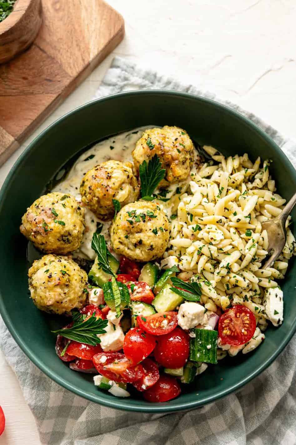 Greek feast with chicken meatballs, tzatziki sauce, cucumber and tomato salad, and lemon feta orzo pasta.