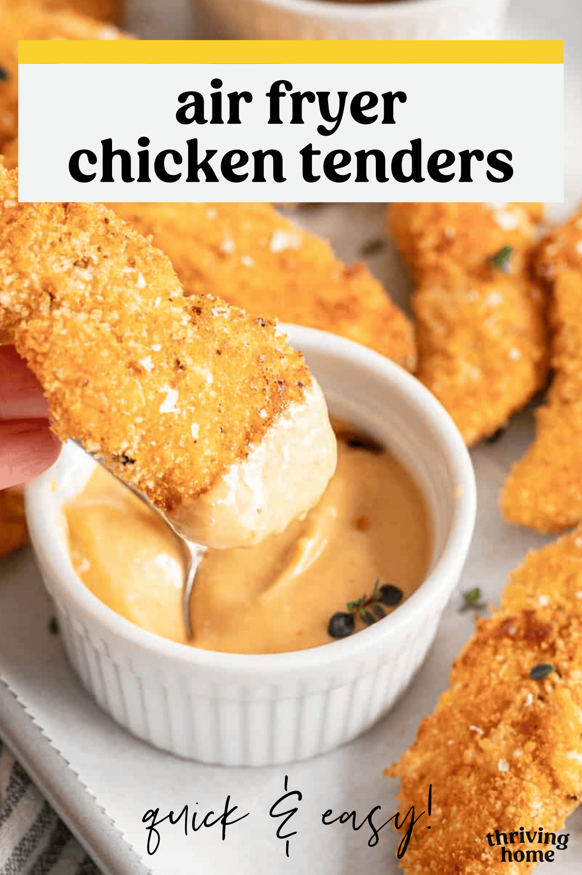 A homemade chicken tender being dipped into cheese sauce.