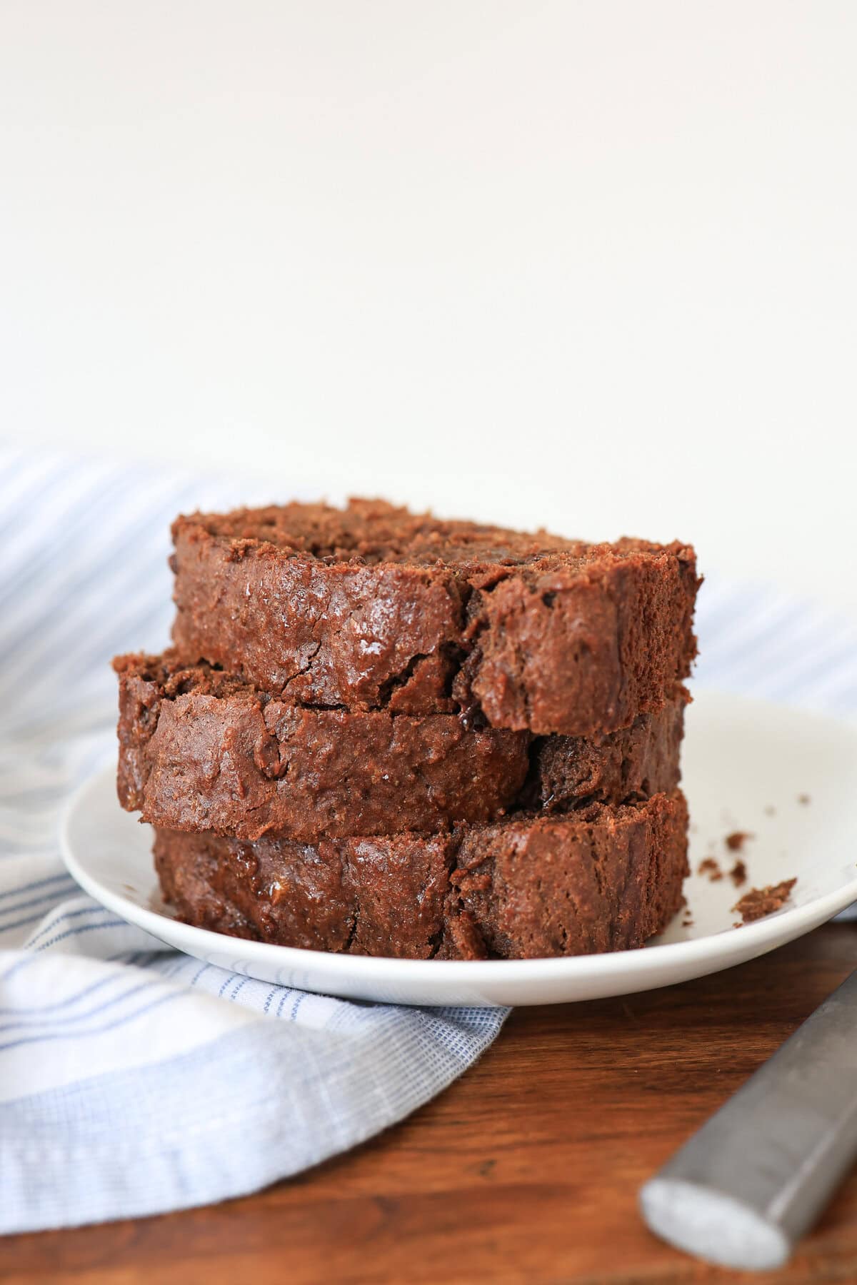 Three slices of chocolate sweet potato bread stacked on a white plate.