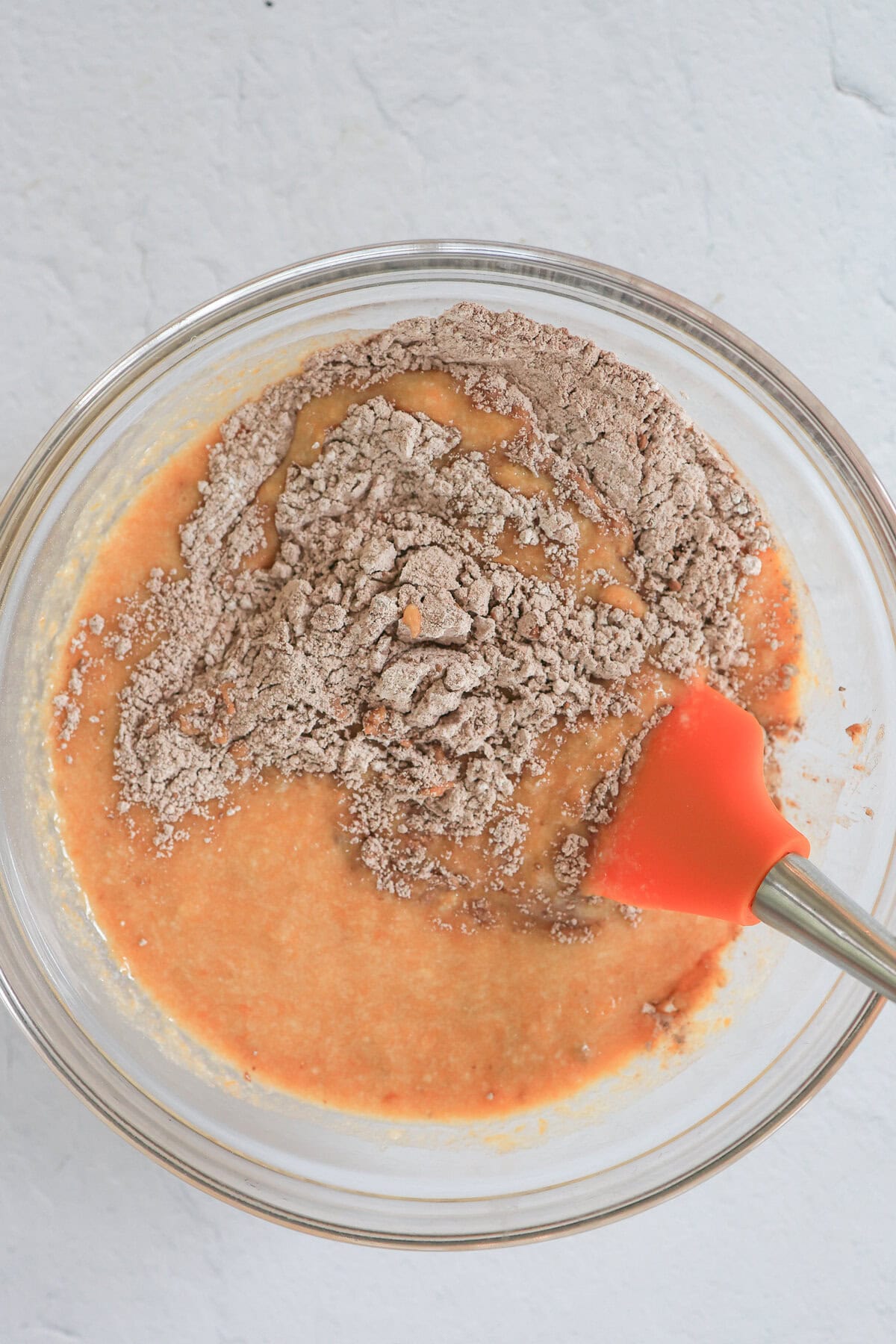 Wet and dry ingredients being mixed together in a glass bowl.