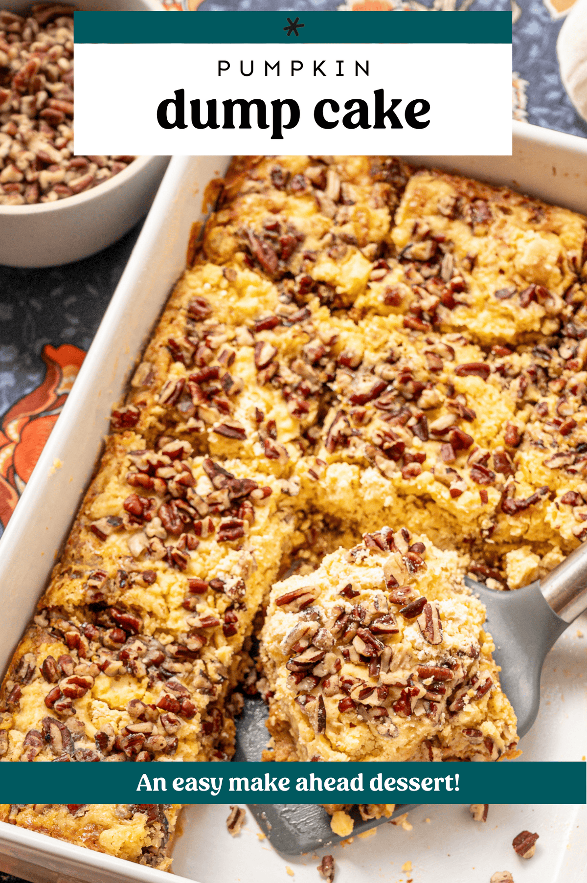 A serving of pumpkin dump cake being lifted by a spatula from a white casserole dish.