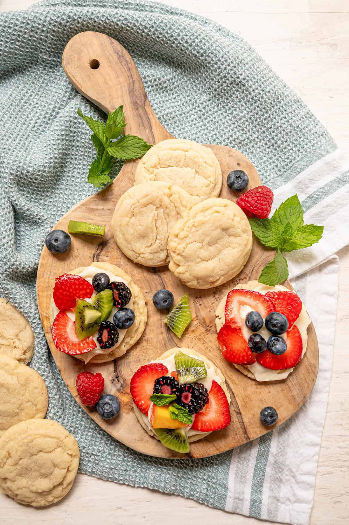 Fruit pizza cookies on a wooden cutting board.