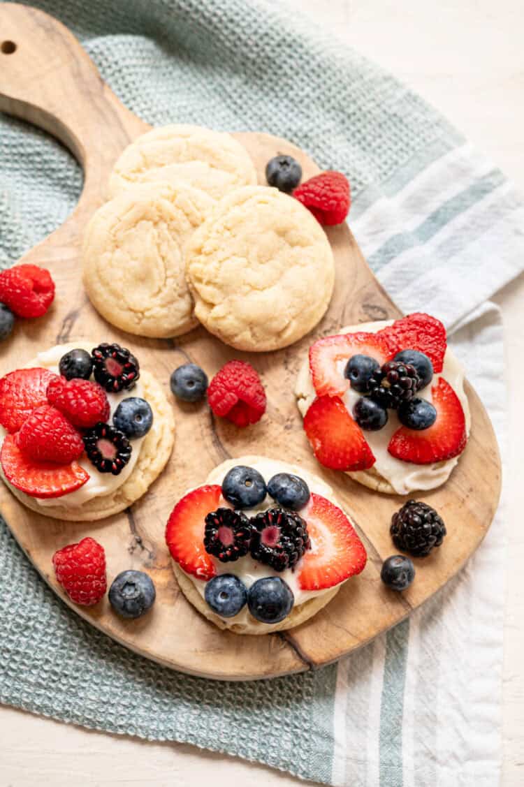 Strawberries, blueberries, raspberries, and blackberries decorating the tops of fruit pizza cookies.