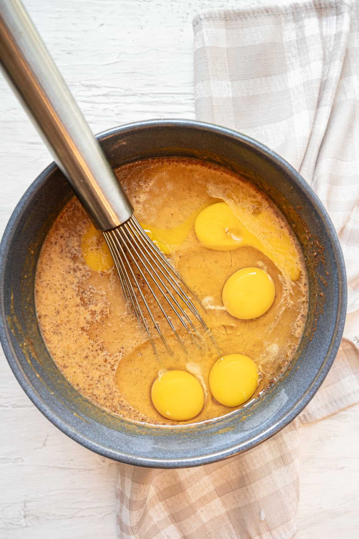Eggs being whisked in to wet ingredients for pumpkin dump cake.