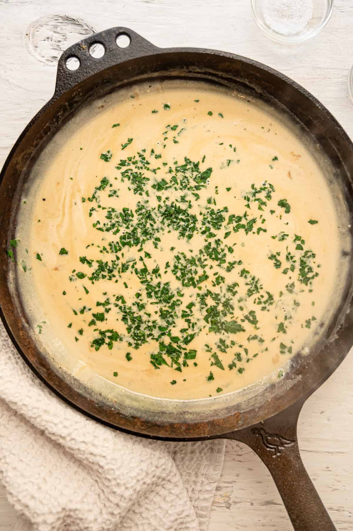 Boursin gravy in a skillet with fresh chopped parsley.