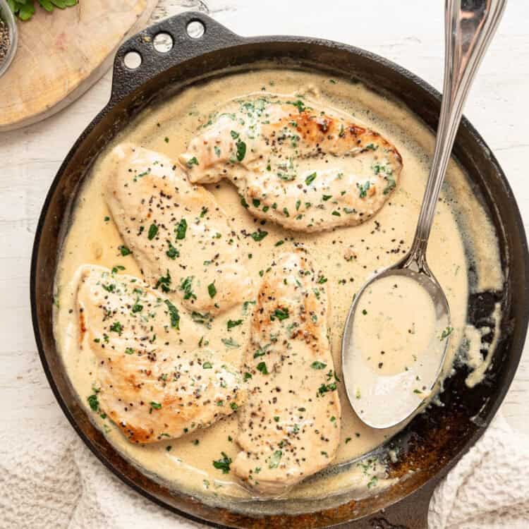 Cooked chicken cutlets in a cast iron skillet with Boursin gravy.