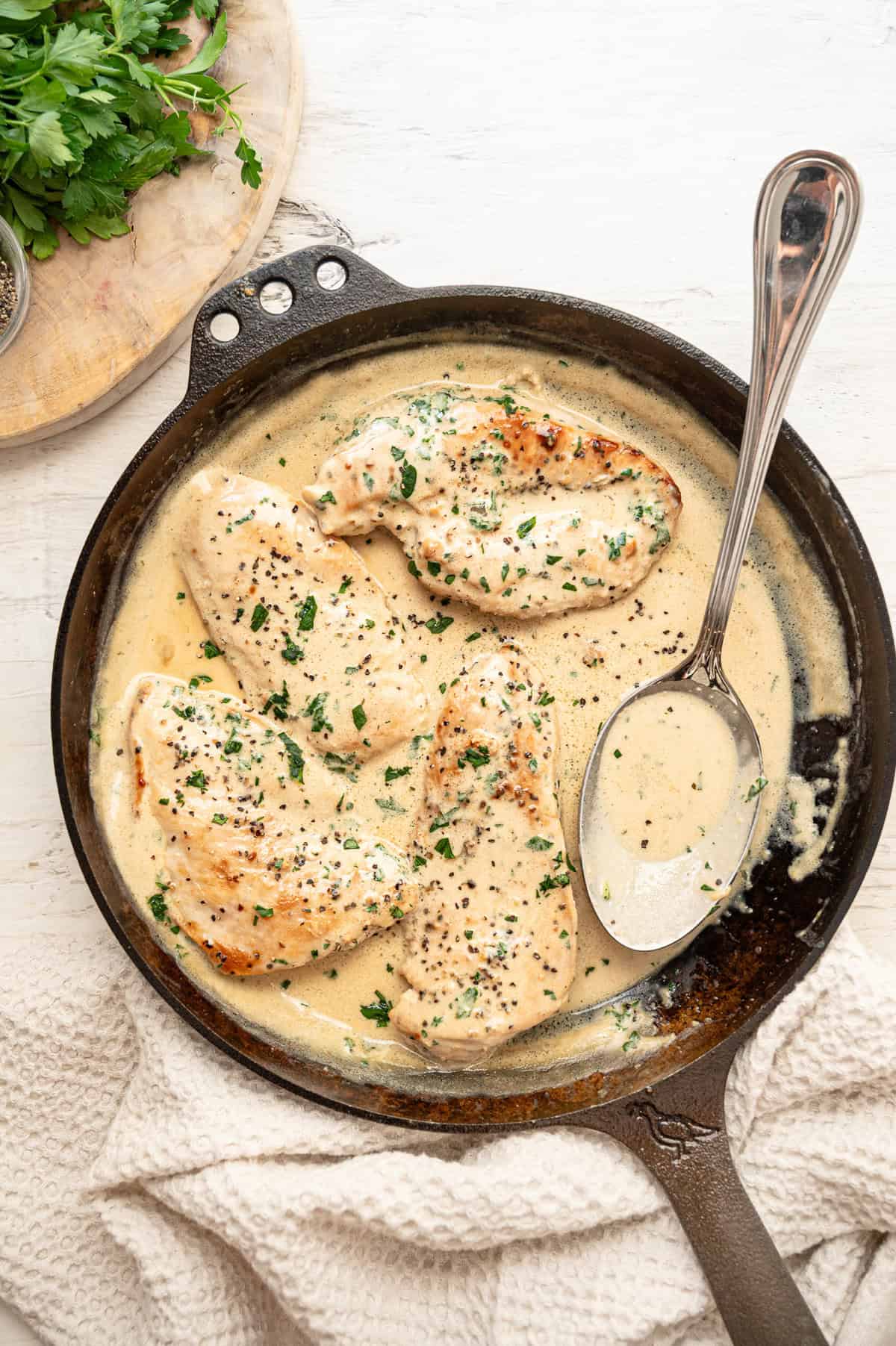 Cooked chicken cutlets in a cast iron skillet with Boursin gravy.