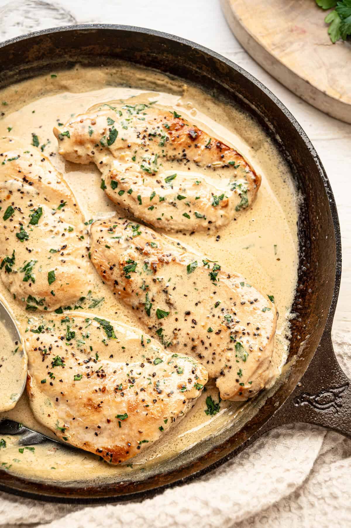 Chicken cutlets smothered in Boursin gravy in a cast iron skillet.
