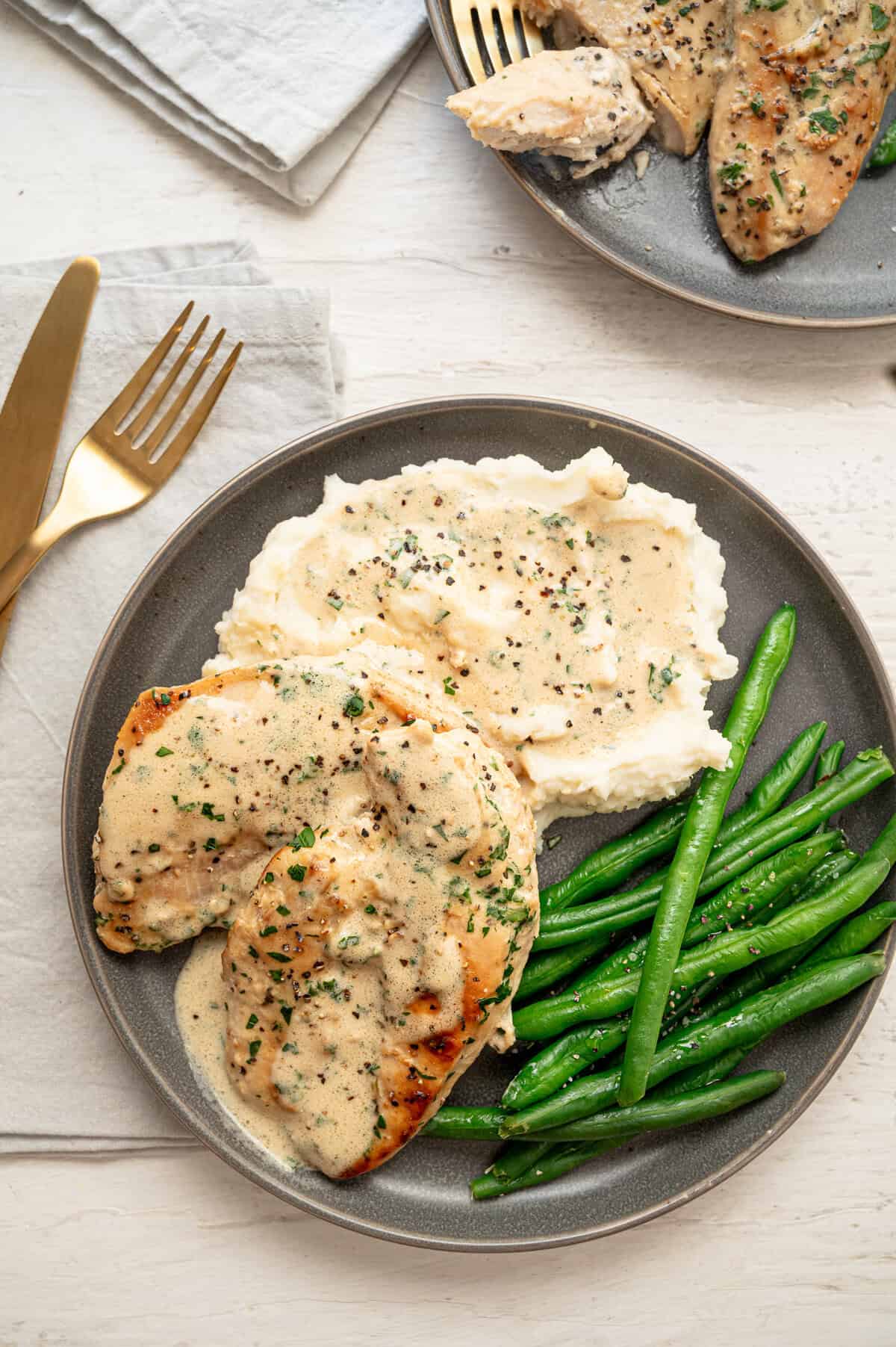 Boursin chicken with green beans and mashed potatoes on a plate.