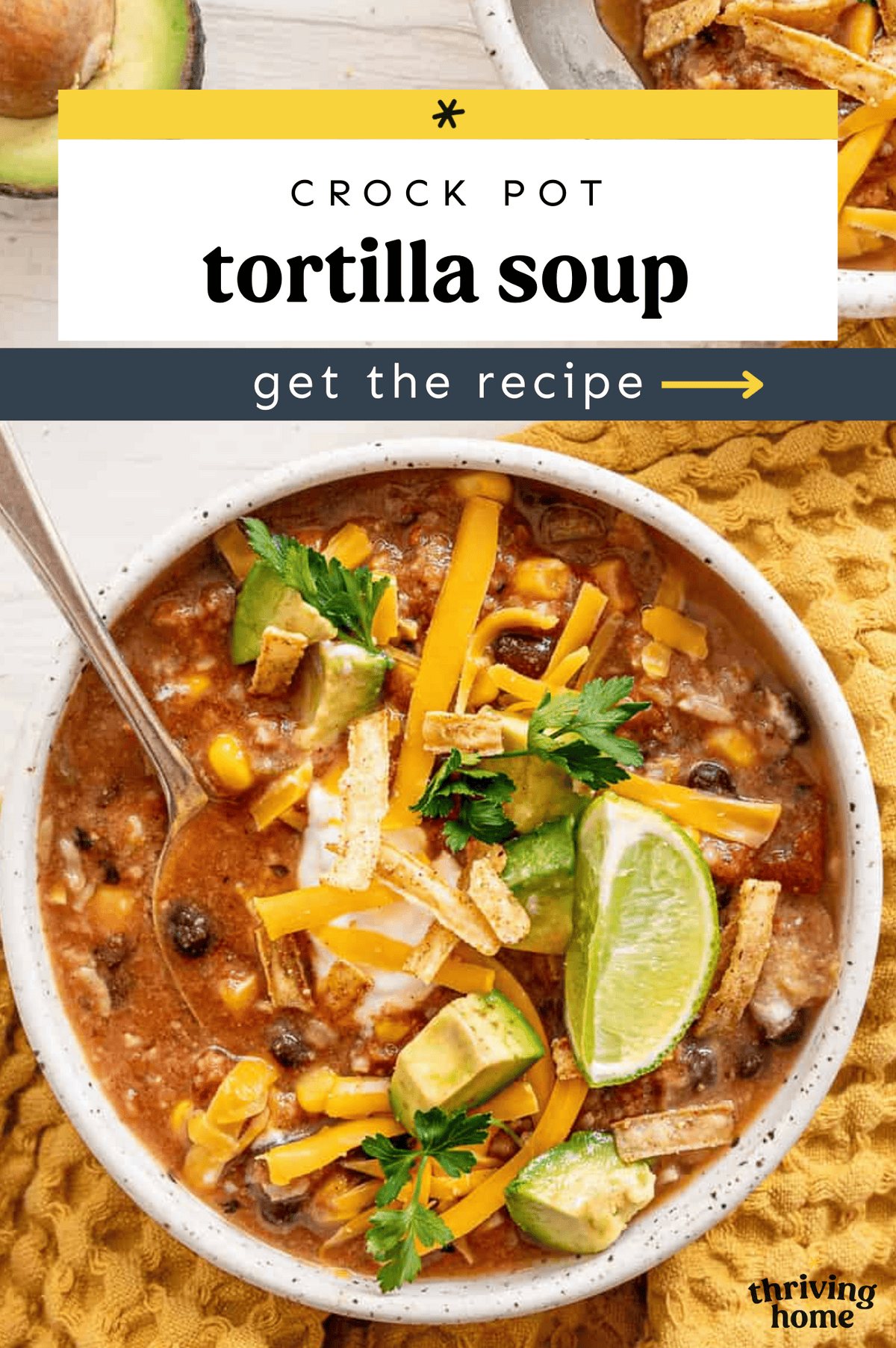 Crock pot tortilla soup in a bowl with shredded cheese, avocado chunks, and tortilla strips on top.