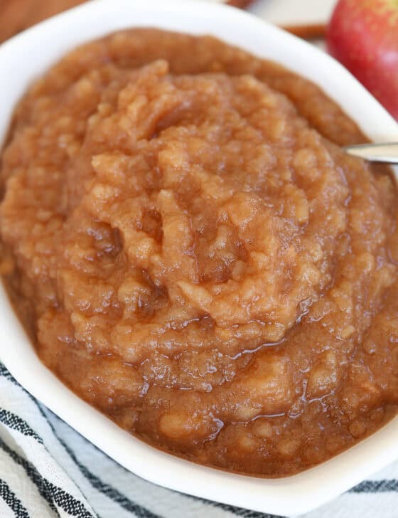 A white serving dish filled with homemade cinnamon applesauce.