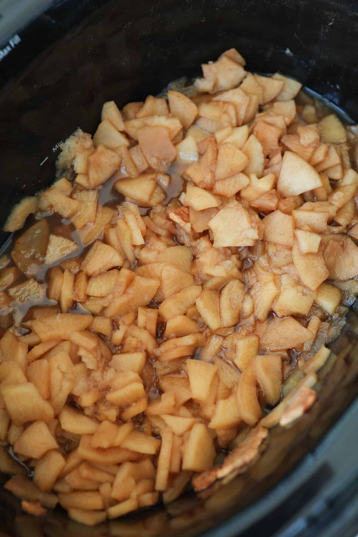 Chopped apples simmering with cinnamon and brown sugar in a crockpot.