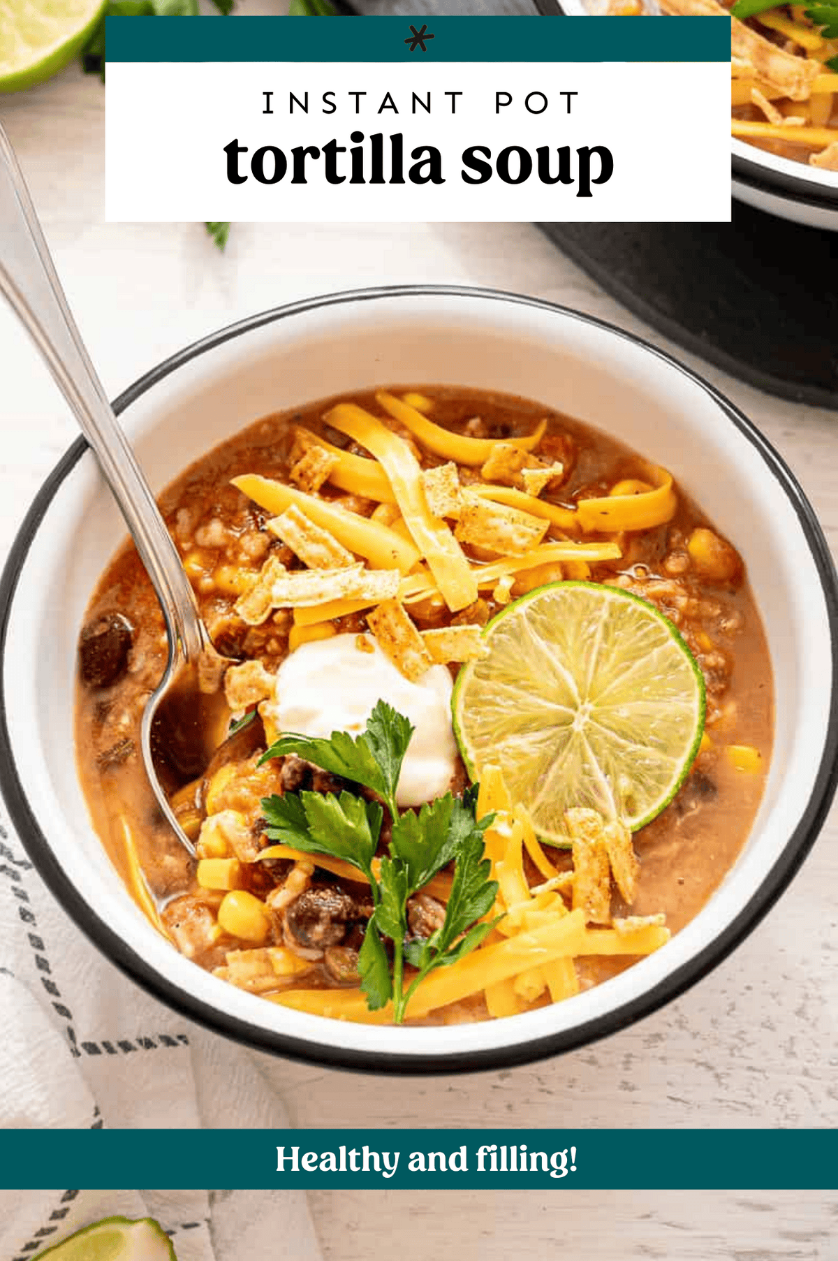 A bowl of tortilla soup with a dollop of sour cream, tortilla strips, and shredded cheese on top.