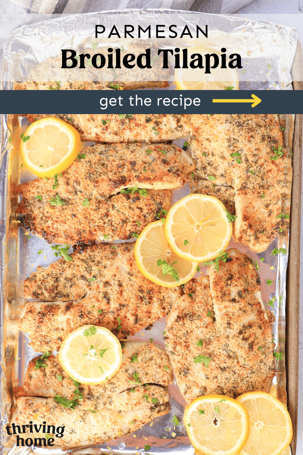Parmesan broiled tilapia filets on a foil-lined baking sheet with chopped fresh parsley sprinkled on top and lemon slices on the side.