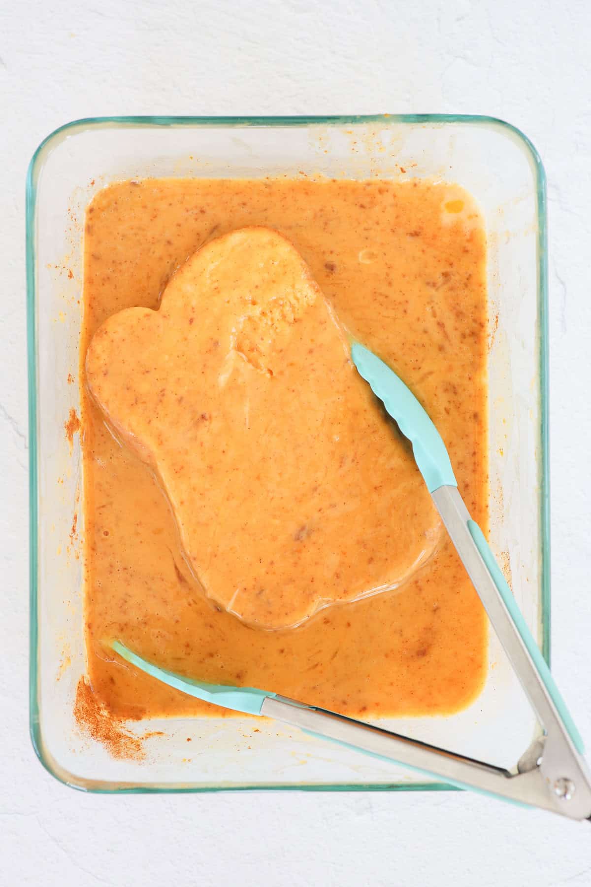 Bread being dipped in an egg and pumpkin mixture to make french toast.