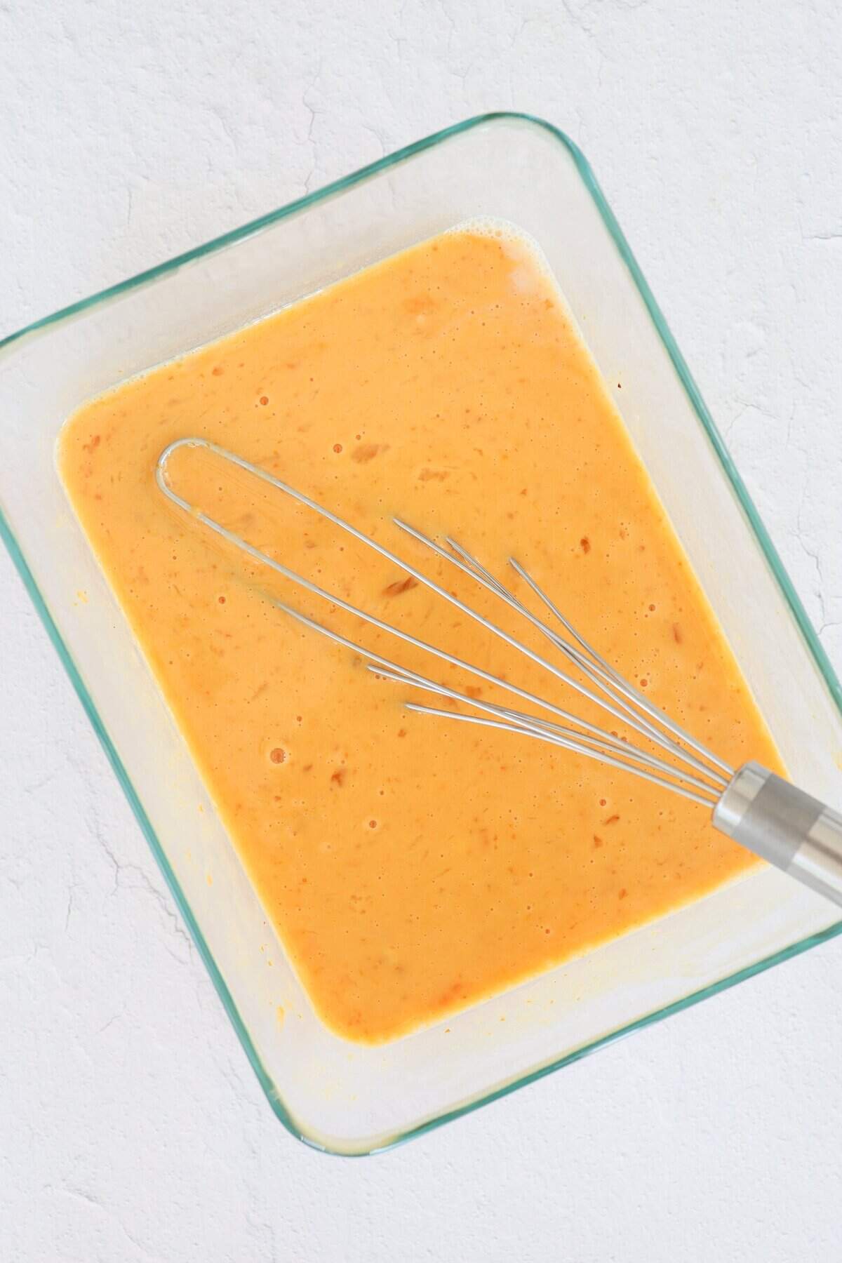 A shallow baking dish with eggs and pumpkin being whisked together for french toast.