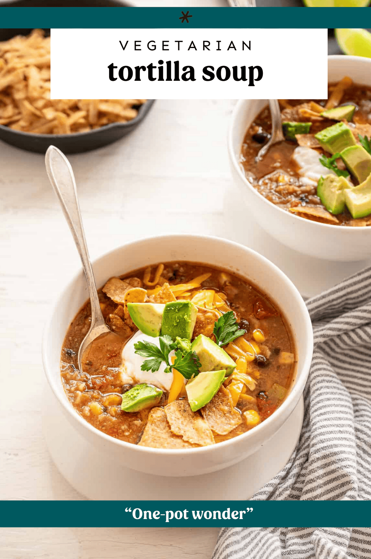 A bowl of tortilla soup with avocado chunks and tortilla chips on top.